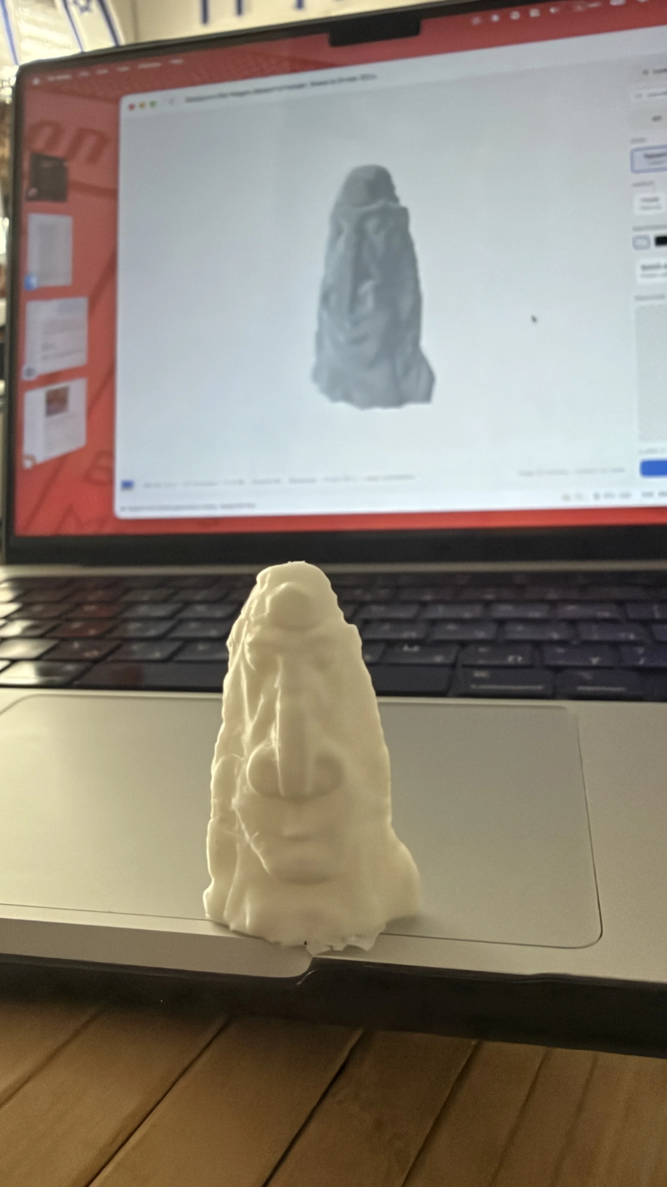 The generated statue 3D printed in white, standing in front of the model on screen