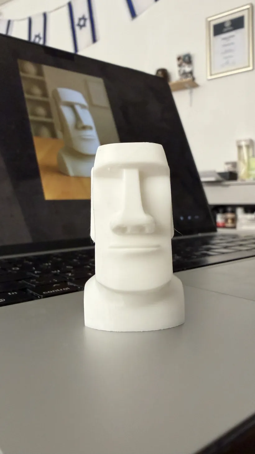 The finished object, 3D printed in white filament next to the laptop